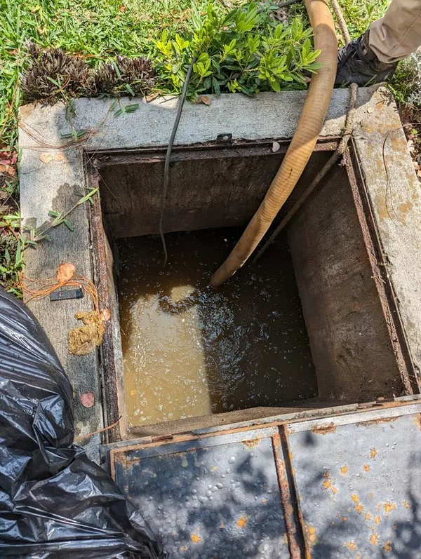 Suction hose clearing a blocked drainage chamber with the cover lifted (illustrative image)