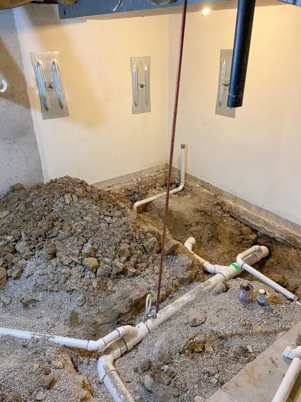 New PVC waste pipework laid in an opened floor during a bathroom plumbing installation (illustrative image)