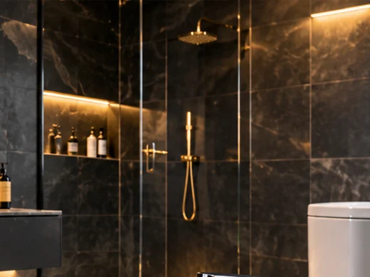 Dark marble-effect wall tiles in a walk-in shower with a gold shower set (illustrative image)