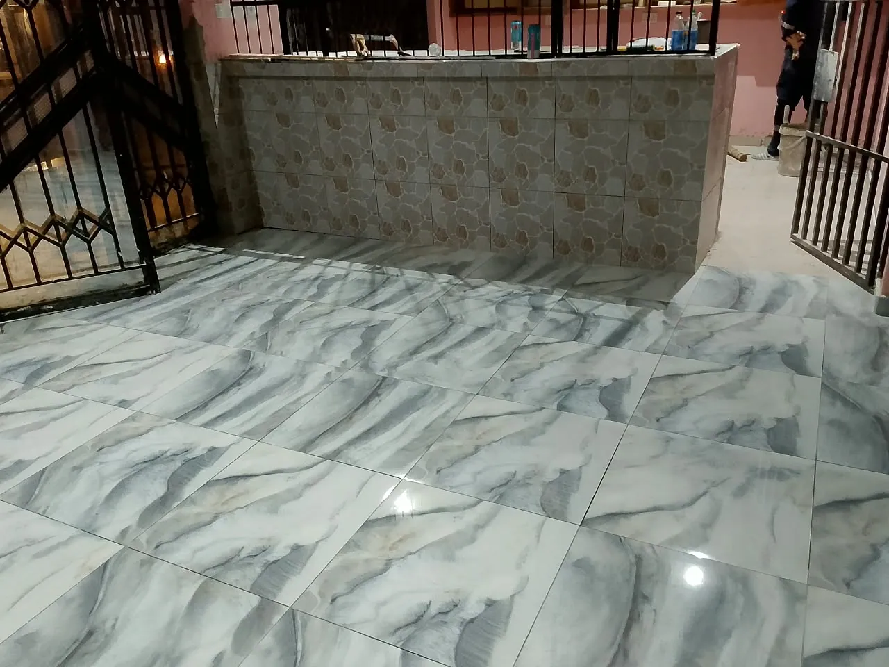 Large-format marble-look floor tiles laid on a patio beside a stone-pattern tiled wall